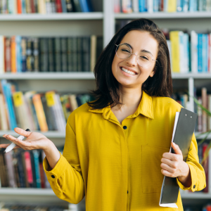 librarian holding some books in front of a shelf.