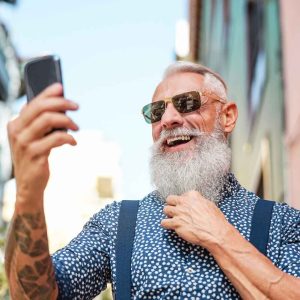 Older man walking down the street using a cell phone